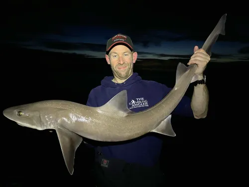 man holding big shark in the dark