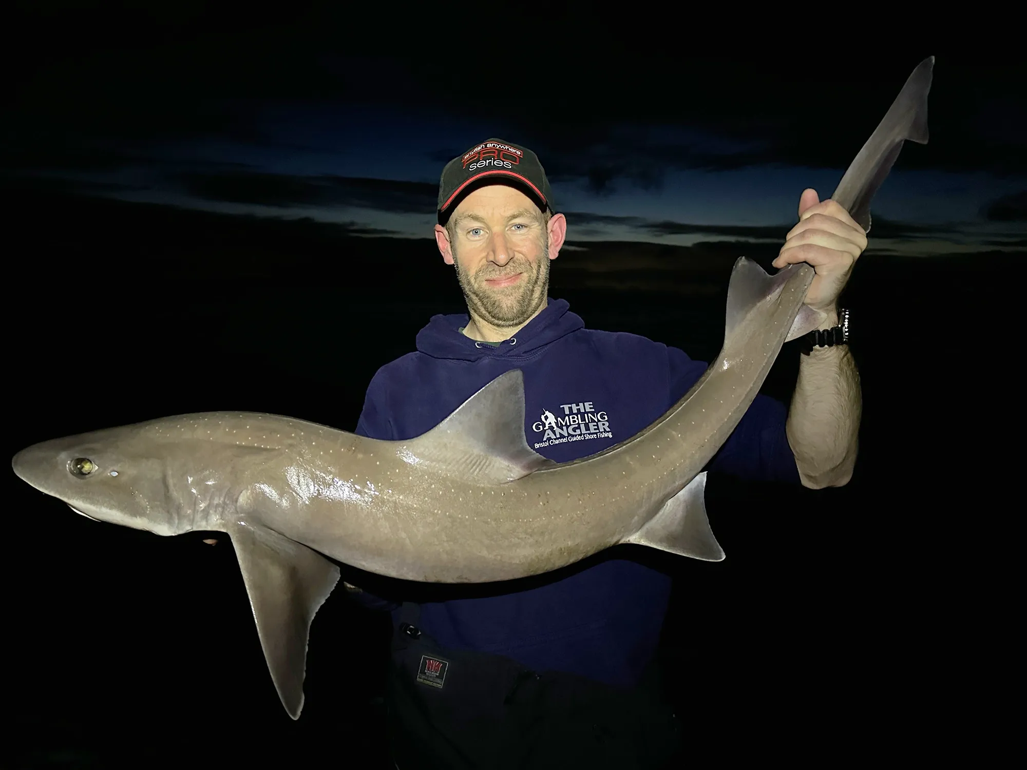 man holding big shark in the dark
